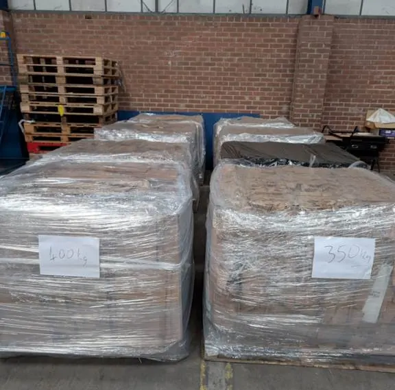 Cardboard bale weight — wrapped bales on pallets with handwritten weight labels