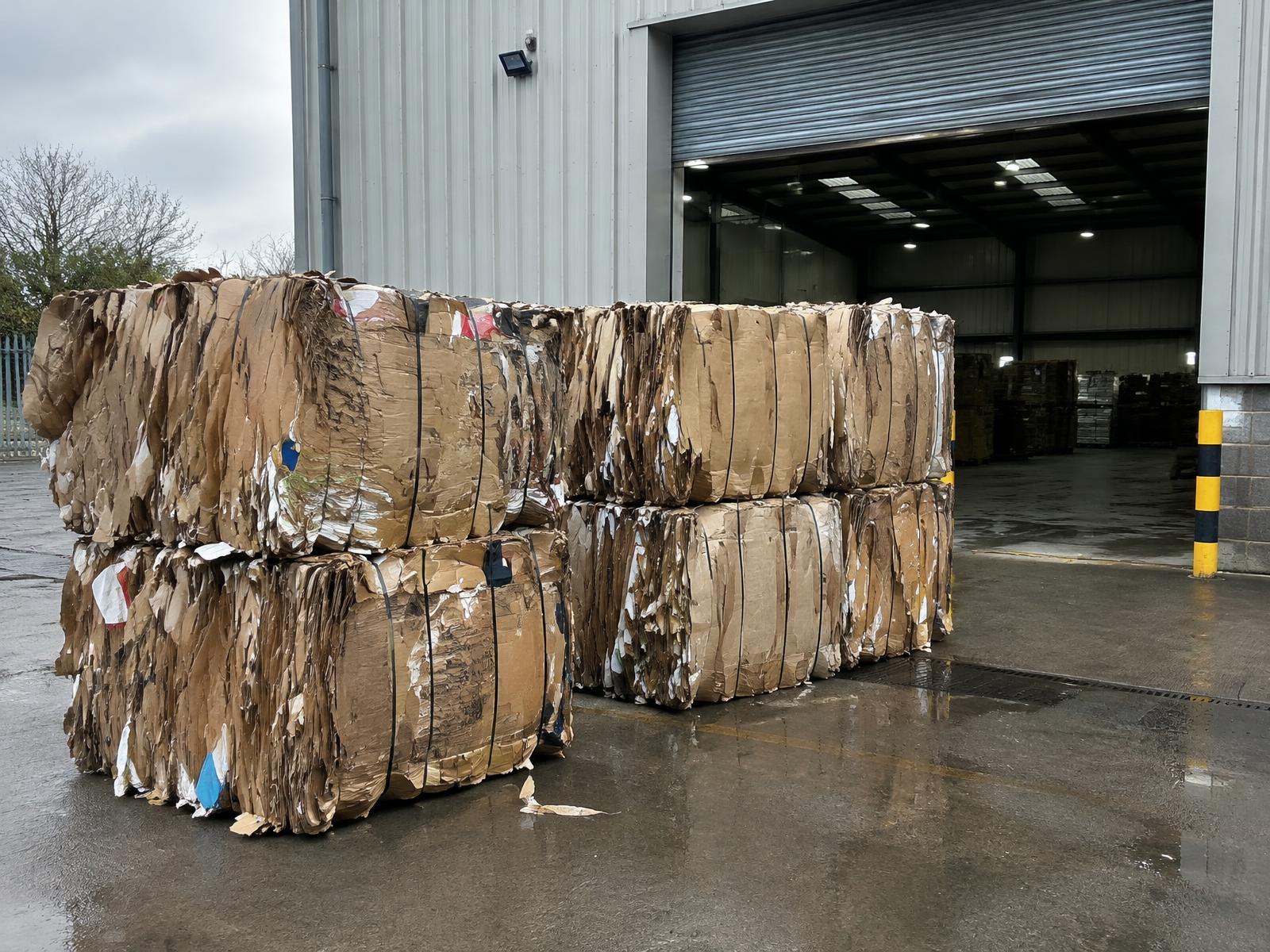 Cardboard bale collection requirements — strapped cardboard bales staged at a loading bay