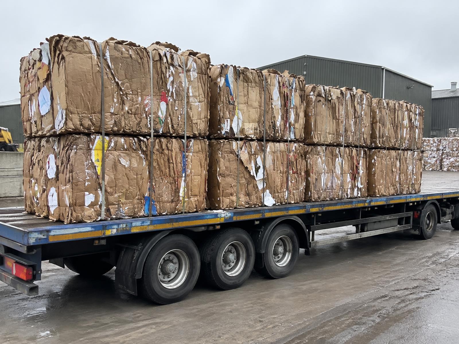 Cardboard balers — strapped cardboard bales loaded on a trailer for transport
